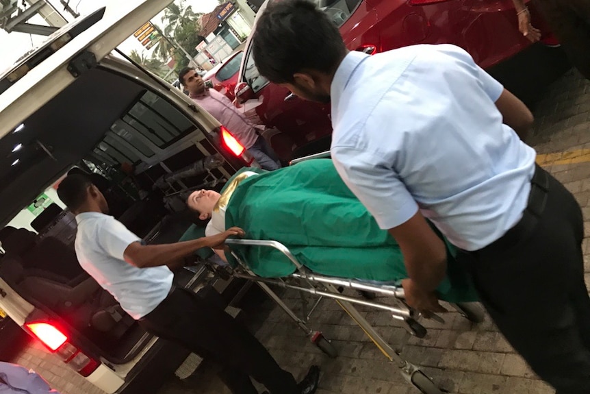 A young white woman is wheeled into an ambulance on a stretcher